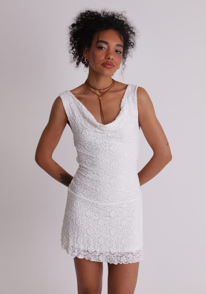 Menina negra vestindo vestido branco de renda, curto. Produto com a cor cloud Dancer, a cor de 2026